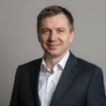Портрет уверенного российского бизнесмена с дружелюбным взглядом на нейтральном размытом фоне в студии