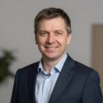 Портрет уверенного российского бизнесмена с дружелюбным взглядом на размытом нейтральном фоне в студии